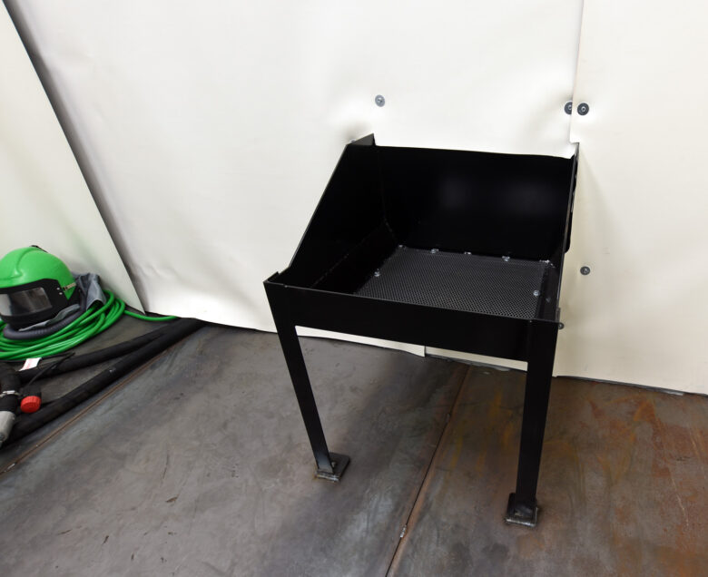 A floor-mounted media reclaim hopper. Hoppers can be recessed (deep pit required) or floor mounted (no pit required). The reclaim system then feeds the recycled media back into the blast machine. 